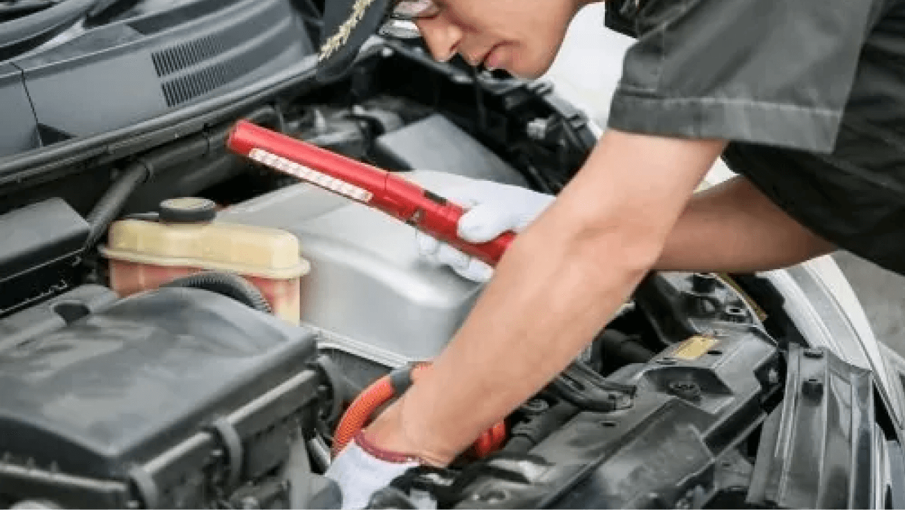 ボンネット内を照らして点検する整備士